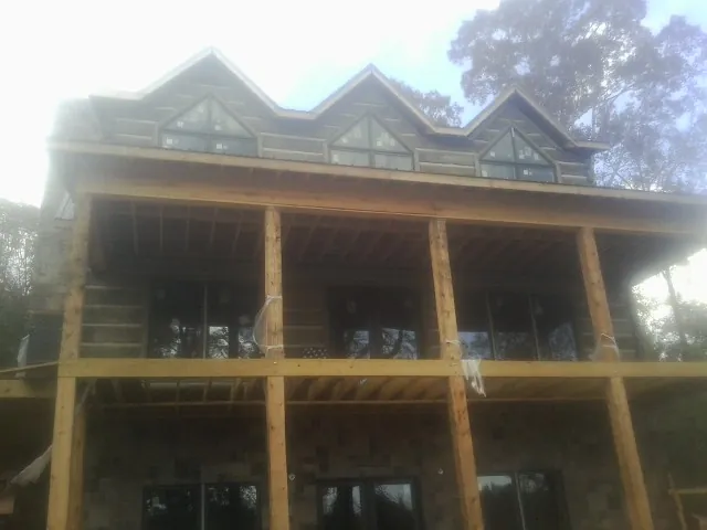 Dormers and porch framing on a large log home under construction — Roof Coating work by our crew in Olin
