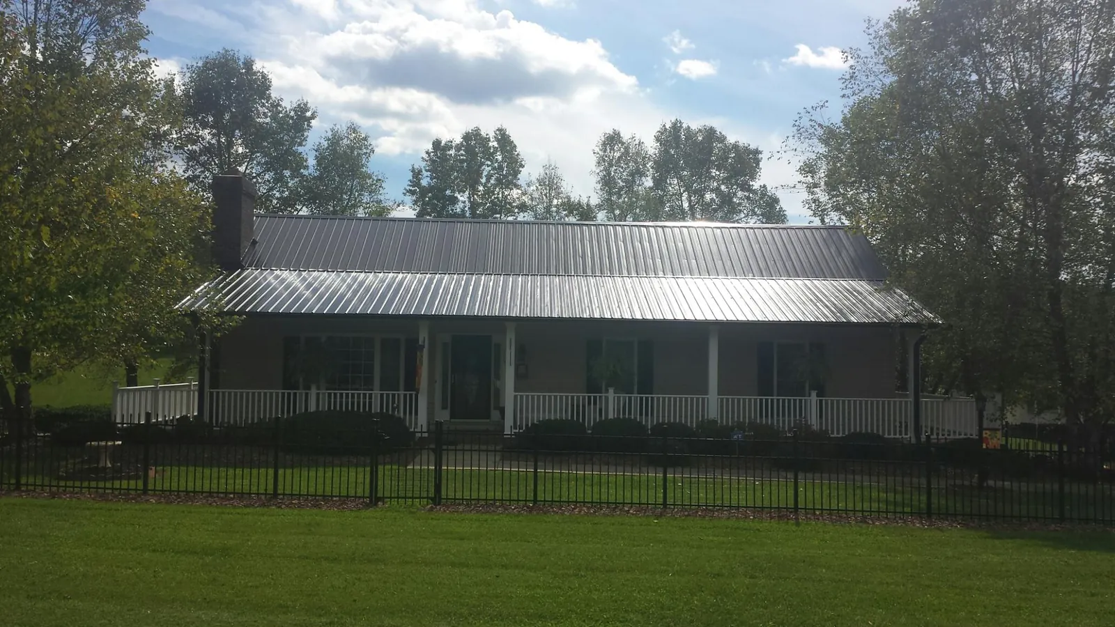 Gray metal roof on a brick ranch with a full width front porch — Gutter Guard Installation work by our crew in Olin